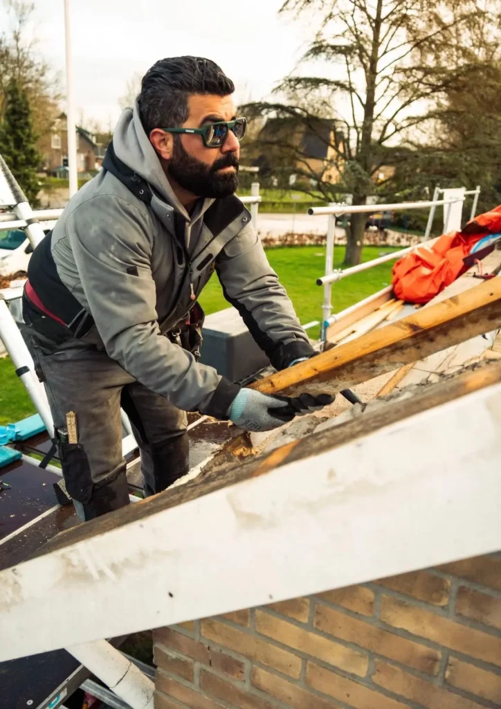 Dakdekker aan het werk op een dak met houten panlatten, vakmanschap bij dakwerkzaamheden