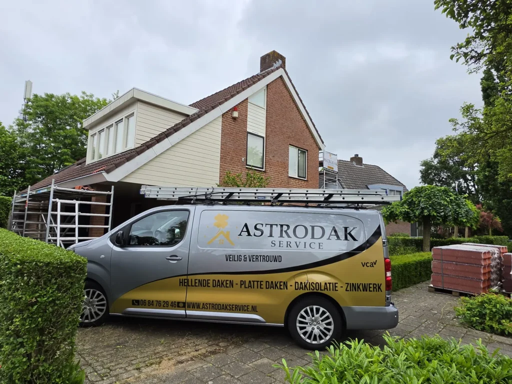 Bedrijfsbus van Astrodak Service voor een woning met dakkapel, met steiger en stapel dakpannen tijdens dakwerkzaamheden