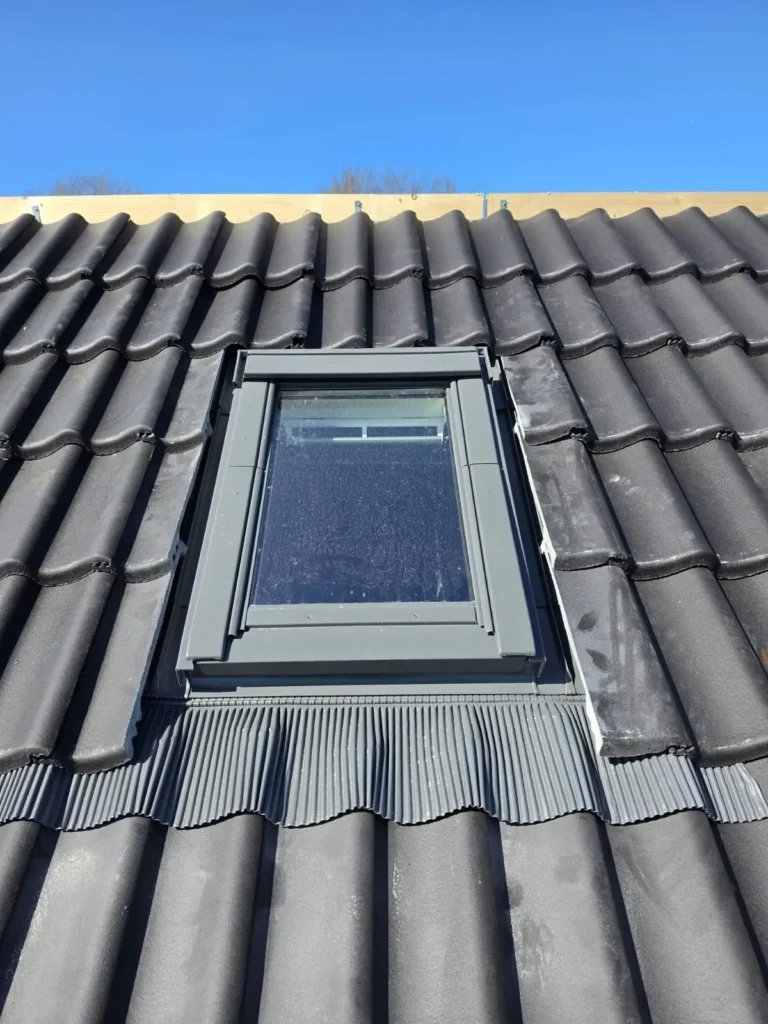 Detail van een dakraam met afwerking in een dak met antracieten dakpannen