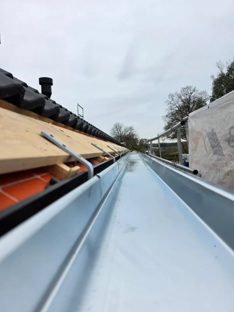 Nieuwe zinken bakgoot langs de dakrand met panlatten en antracieten dakpannen