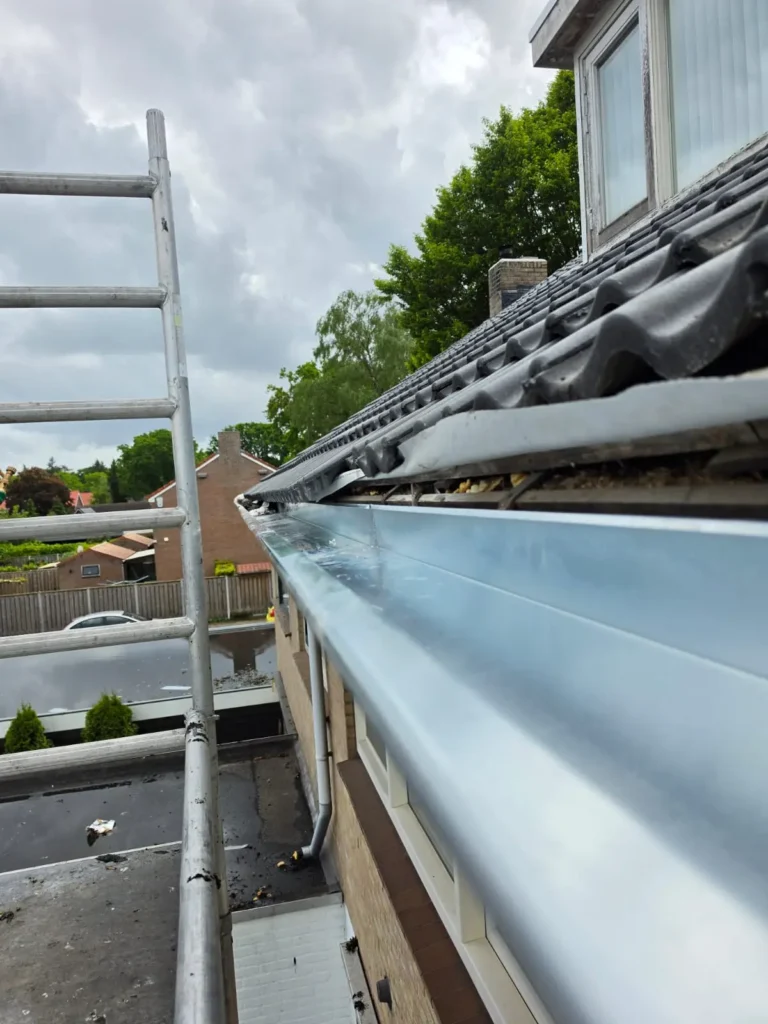 Schoongemaakte zinken dakgoot langs de dakrand met steiger en uitzicht op de straat