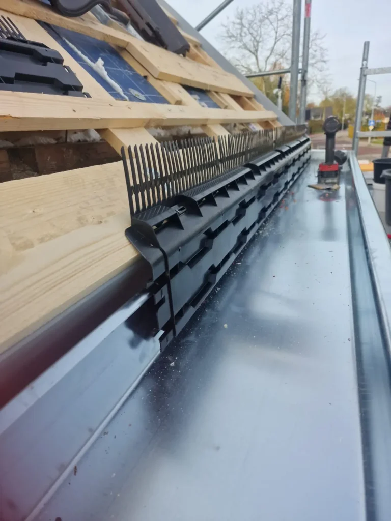 Zinken dakgoot met zwarte vogelwering en ventilatiestrip langs de dakrand