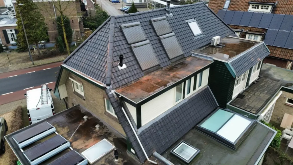 Luchtfoto van een woning met een nieuw dak met zwarte dakpannen, zonnepanelen en dakramen