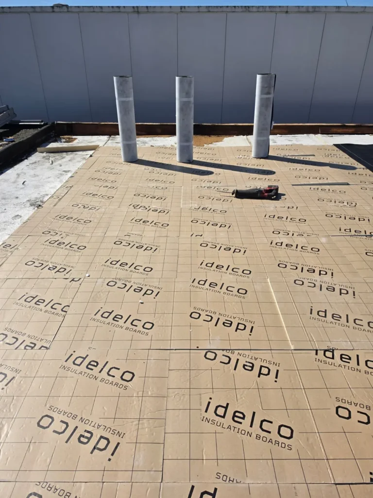 Plat dak met Idelco isolatieplaten en drie dakdoorvoeren tijdens dakisolatie
