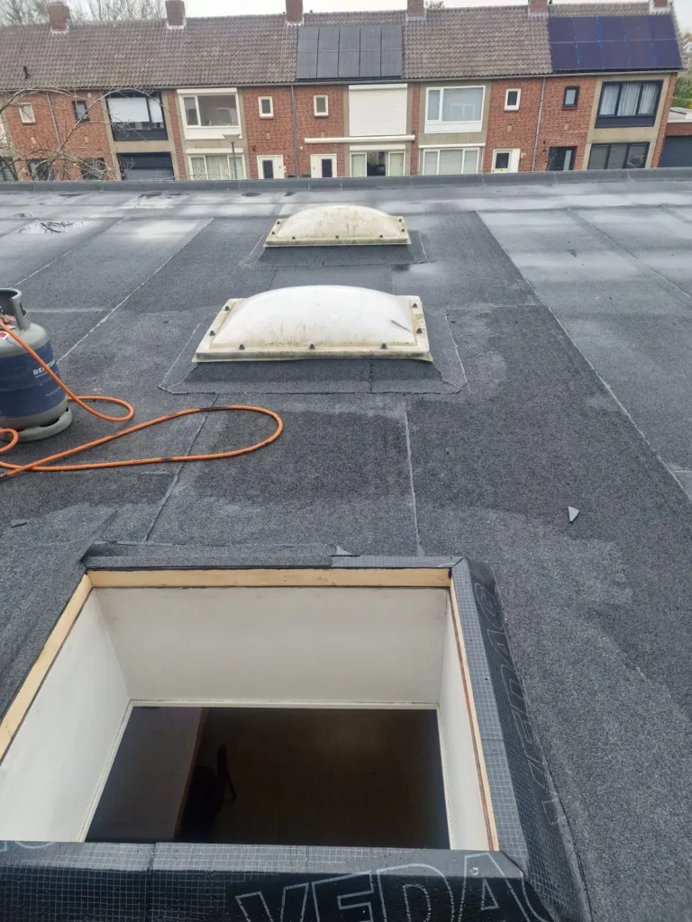 Plat dak met twee lichtkoepels en een dakopening, voorzien van nieuwe bitumen dakbedekking