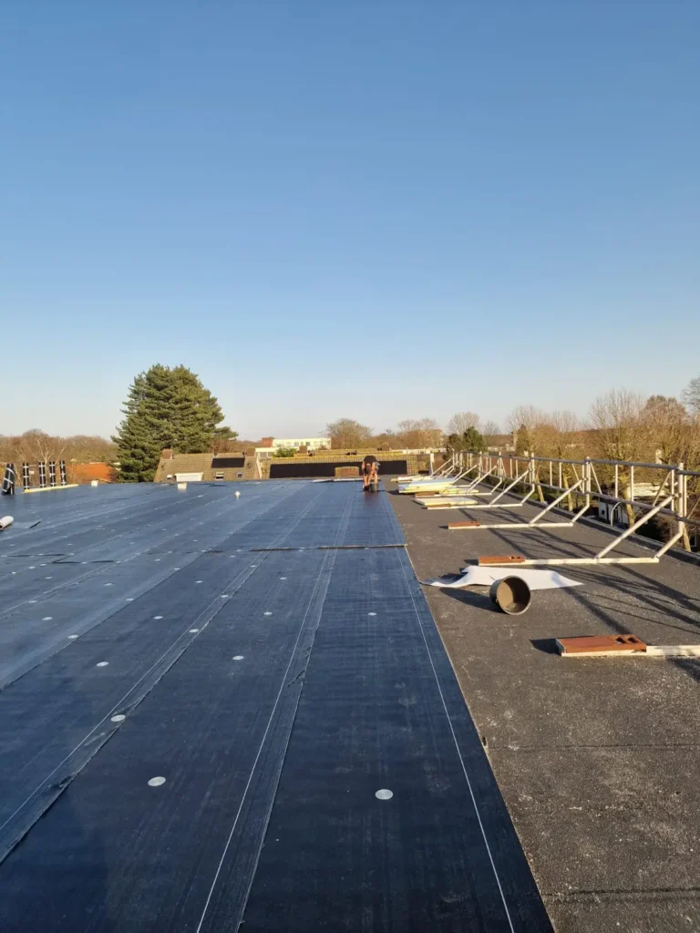 Plat dak met EPDM rubber dakbedekking en montageframes op de achtergrond