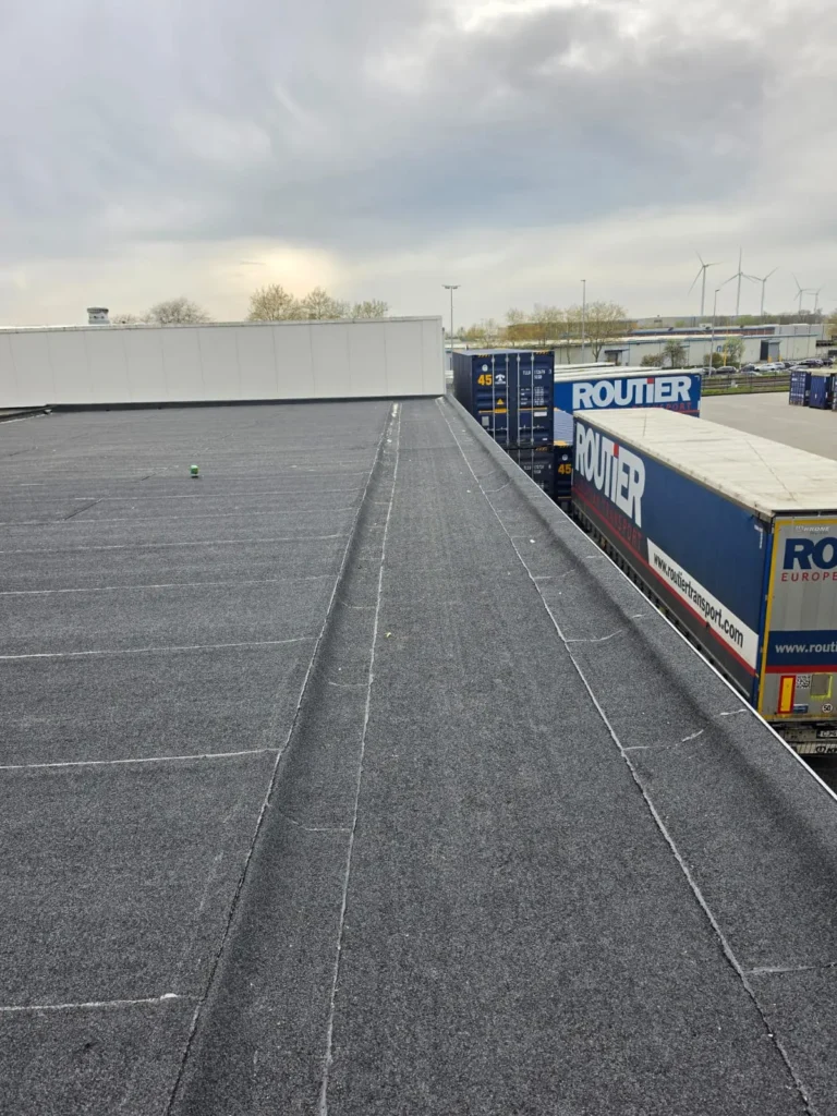 Groot plat industrieel dak met bitumineuze dakbedekking op een bedrijfspand