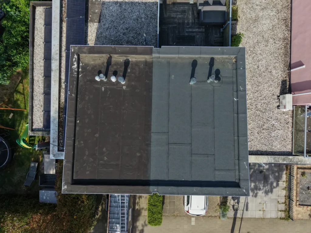 Luchtfoto van een nieuw plat dak met donkere bitumen dakbedekking en dakdoorvoeren